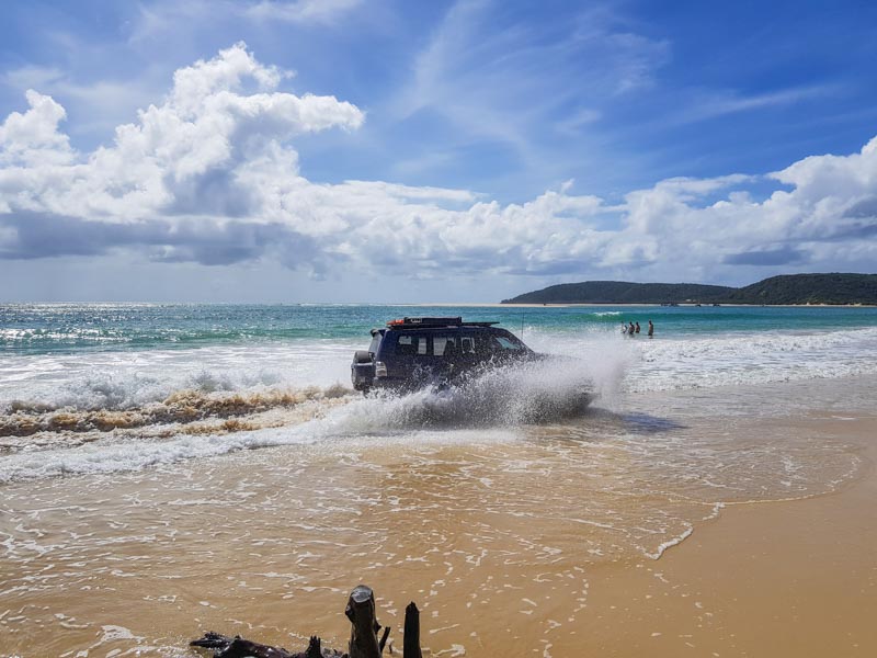 Driving our vehicle through the water to get around the trees on the beach